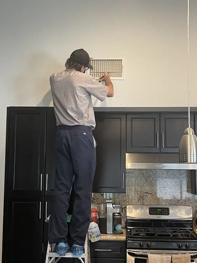 Technician inspecting an air vent during HVAC service in South Lyon